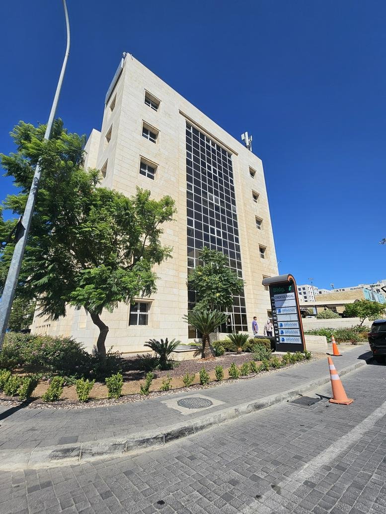 Wide exterior shot of the modern multi-story office building and paved walkway.
