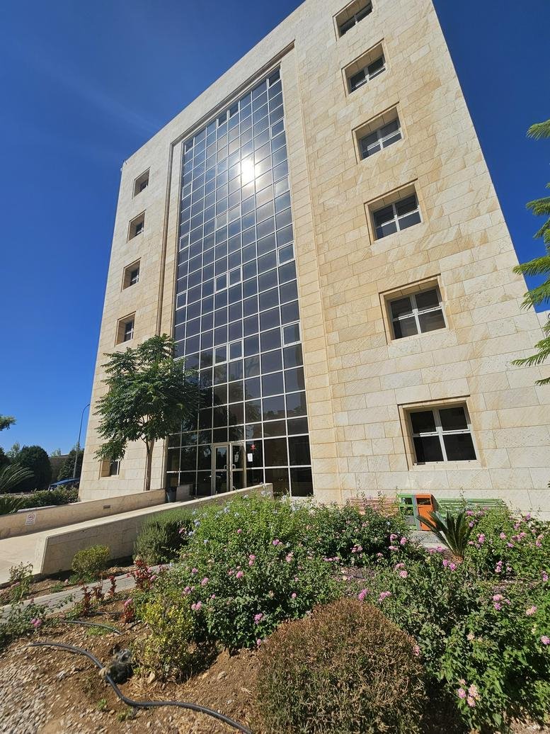 Full exterior of the contemporary stone building under a clear blue sky.
