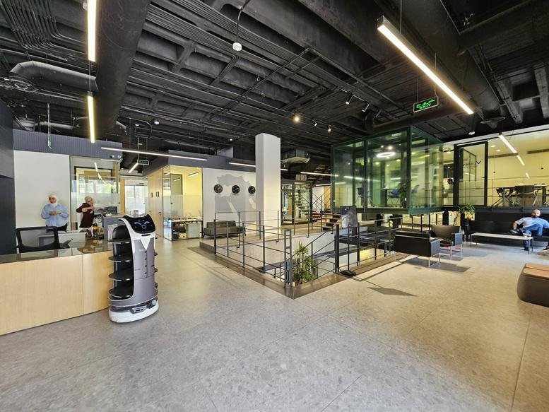 Spacious reception area with a modern service robot and high industrial ceilings at Abdoun Branch, Amman.
