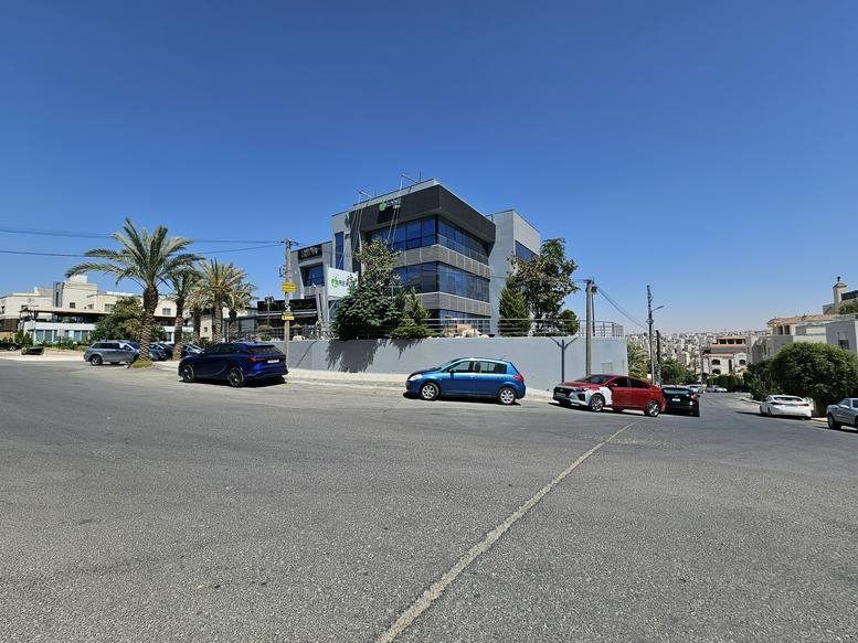 Exterior view of the multi-story grey stone and glass facade of the Abdoun Branch, Amman building.