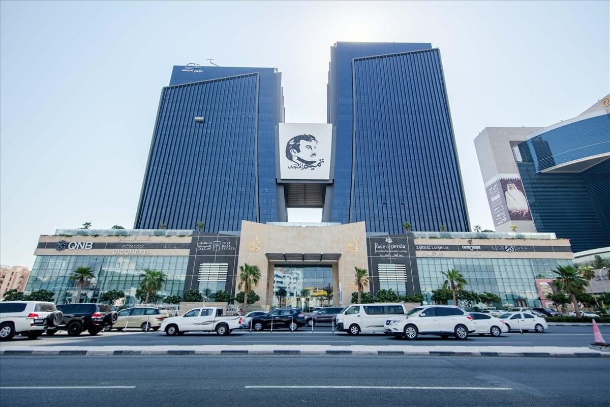 Exterior view of the glass-facade Al Shoumoukh Towers with its distinctive connecting bridge.