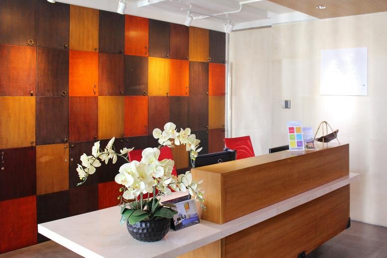 Modern reception desk with a vibrant multi-colored wood panel feature wall and white orchids.