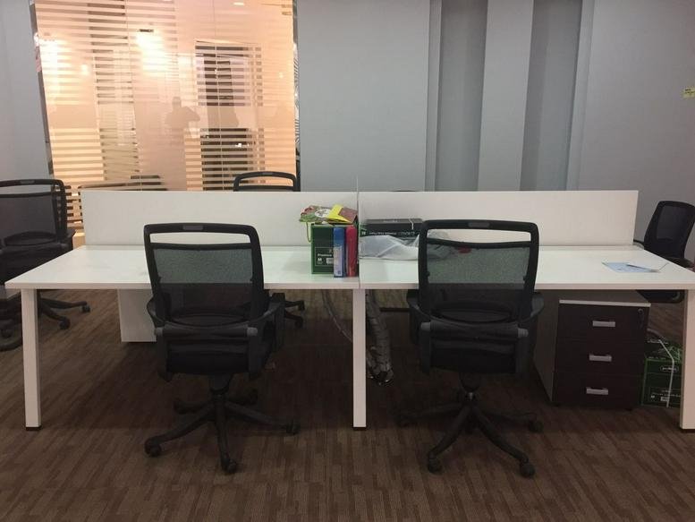 Four-person workstation cluster with white desks and black mesh chairs.