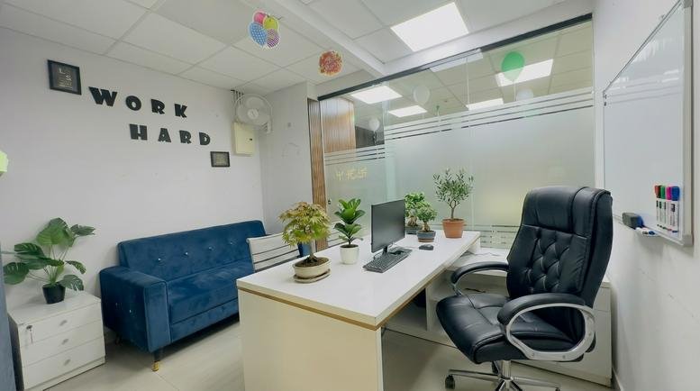 Private office at Vasavi MPM Grand with a blue sofa, white desk, and wall art reading work hard.