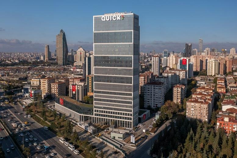 Exterior view of the glass-facade AND Kozyataği building standing tall against a clear blue sky.