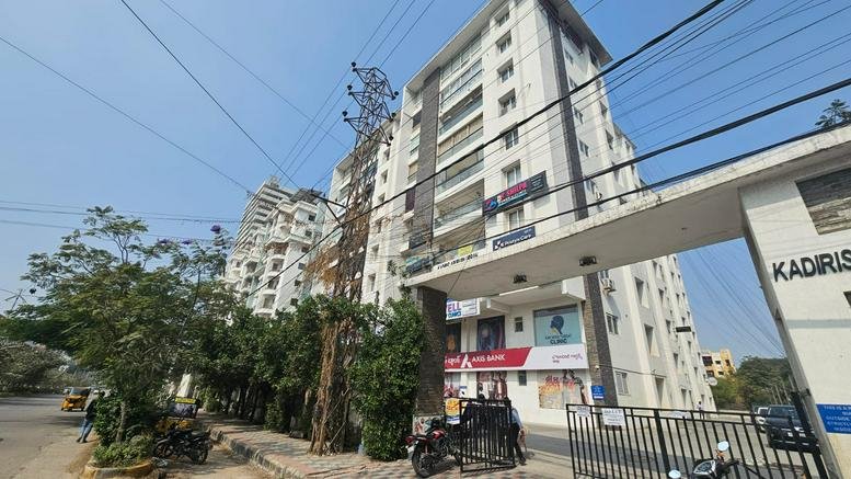 Exterior view of the white high-rise facade of Apurupa Urban with commercial signage.