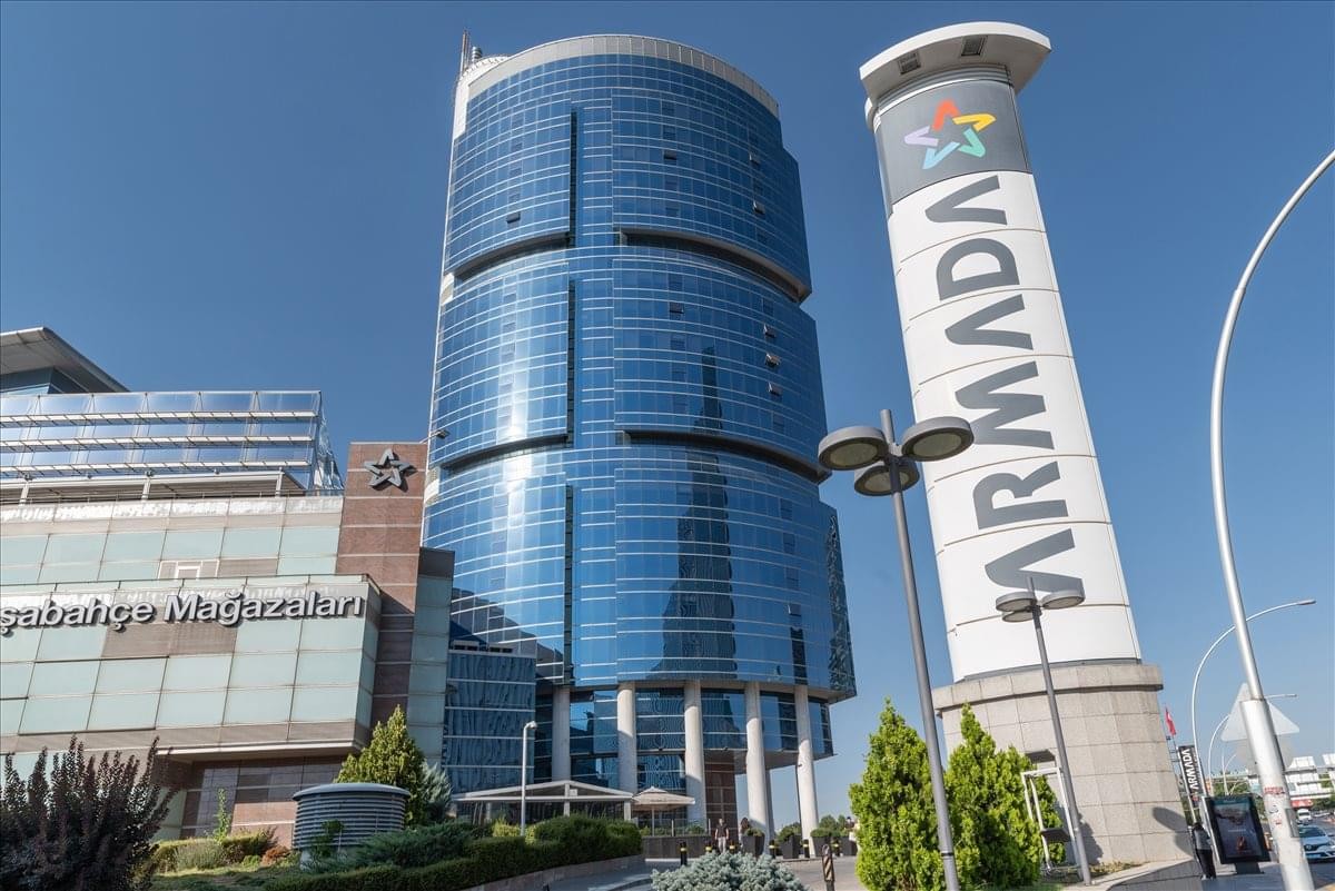Exterior view of the curved glass facade of Armada Is Merkezi under a clear blue sky.