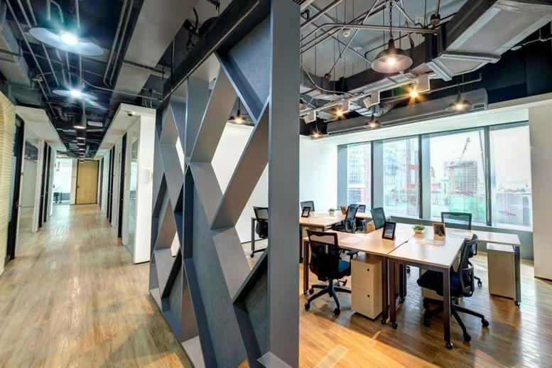 Open-plan workspace at Arthaland Century Pacific Tower with modern geometric partitions.