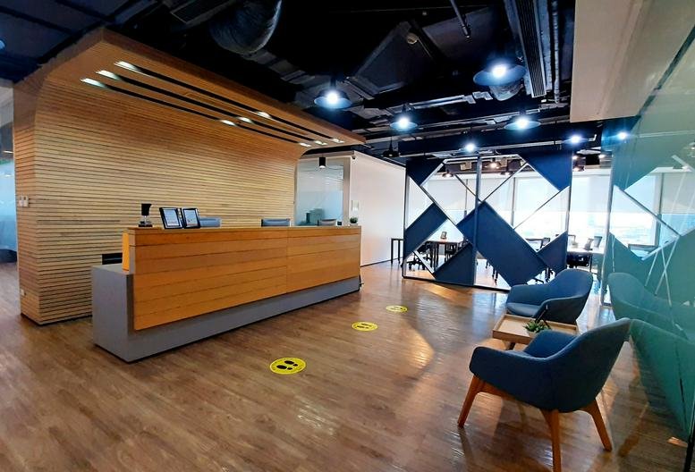Wide view of the wood-paneled reception desk at Arthaland Century Pacific Tower with blue accent seating.