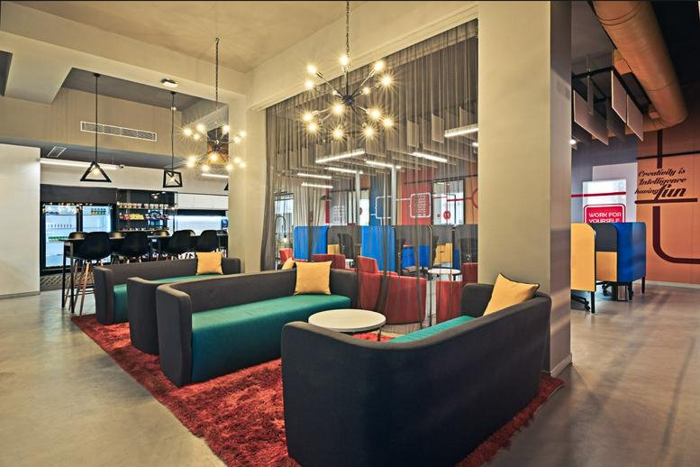 Interior view of the modern lounge and breakout space at Aston Building featuring teal sofas.