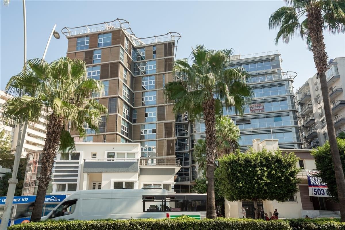 Exterior view of the Ataturk Caddesi, Mimar Semih Rustem Is Merkezi building with surrounding palm trees.