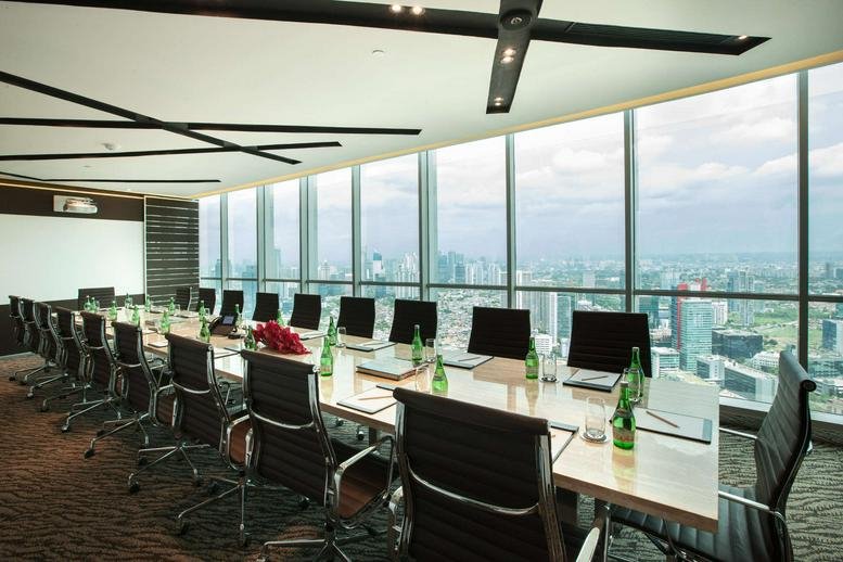 Spacious boardroom with a long table and floor-to-ceiling windows overlooking the city.