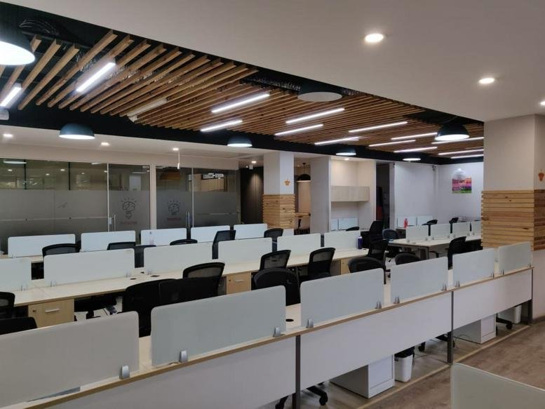 Large open-plan workspace with multiple desk banks and slatted wood ceiling details.