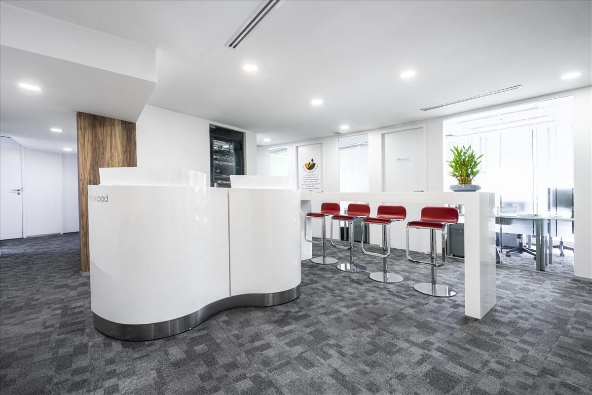 Modern reception lounge featuring a curved white desk and red bar stools.