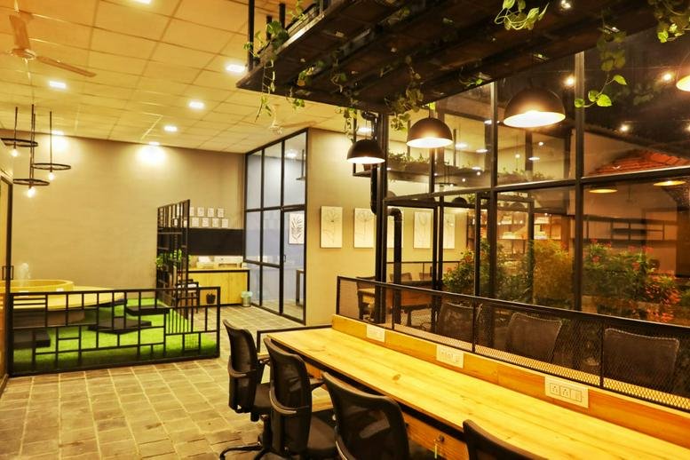 Spacious communal area at Wabi Sabi, Beed By Pass Road with warm lighting, wooden desks, and indoor plants.