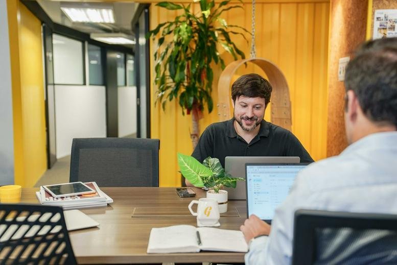 Spacious communal area at Beverly House with modern desks, plants, and yellow accents.