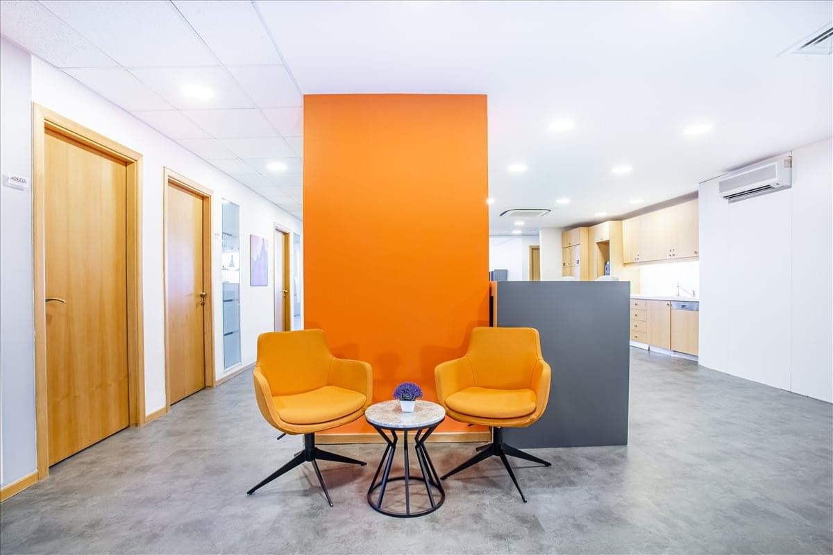 Bright breakout area at BeybiGiz Plaza featuring an orange accent wall and stylish armchairs.