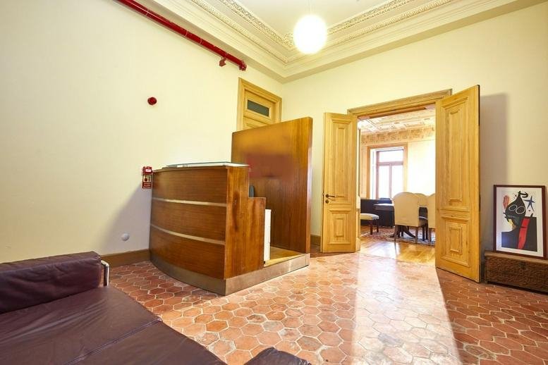 Reception area at 56/58 İstiklal Caddesi featuring a curved wooden desk and patterned terracotta tile flooring.