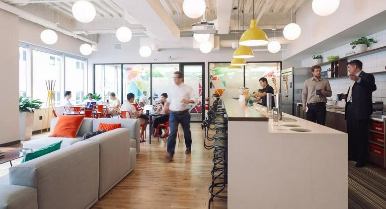 Bright communal lounge and cafe at Sambhav BKC with yellow pendant lights and comfortable sofa seating.