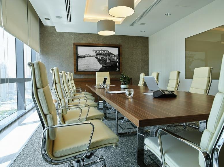 Spacious boardroom at Boulevard Plaza, Tower 2 featuring a long wooden table and cream leather chairs.