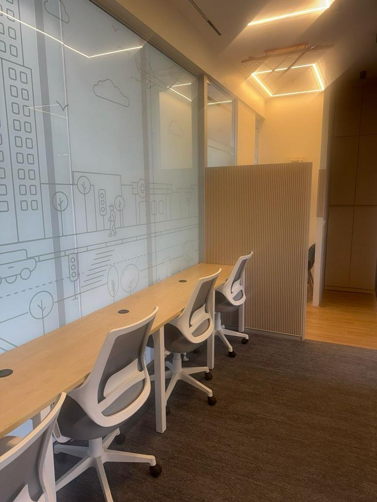 Bright coworking area at Bremen Chowk, Aundh, Pune, India with wooden desks and artistic glass partitions.