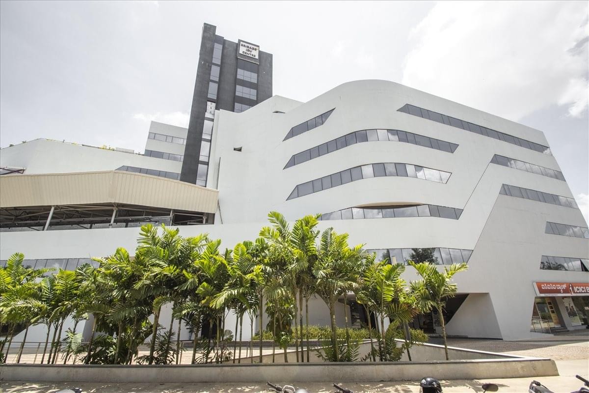 Exterior view of the modern, curved white facade at Brigade IRV, Nallurhalli.