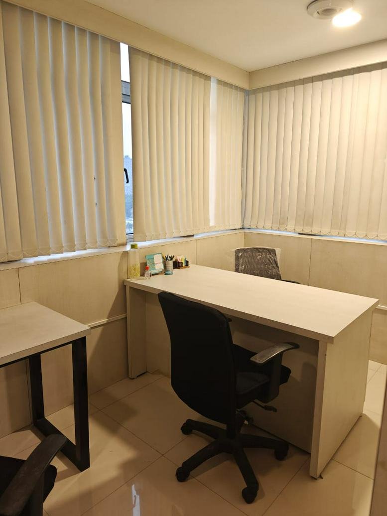 Private office at Industry House with a desk, black chair, and vertical blinds.