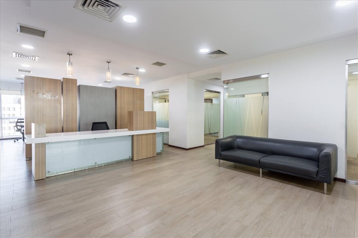 Spacious reception area with a long white front desk and a dark leather sofa at BRR Towers.