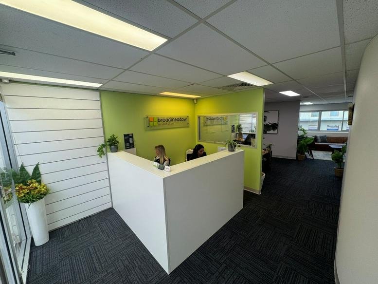 Bright reception area at 5 Brunker Road, Broadmeadow with a white desk and lime green feature wall.