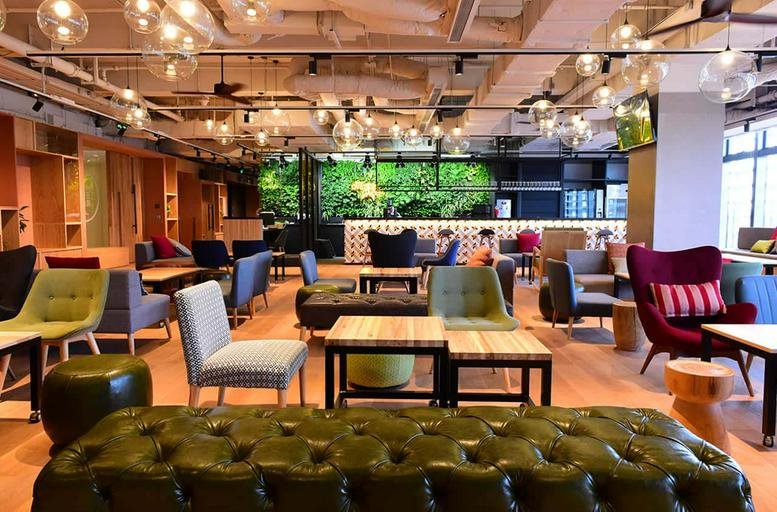 Spacious communal lounge with colorful armchairs and industrial lighting at Building 1, 818 Shenchang Road, Shanghai.