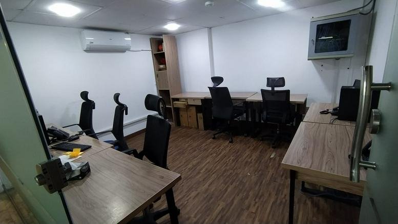Shared office with wooden flooring and multiple desks.