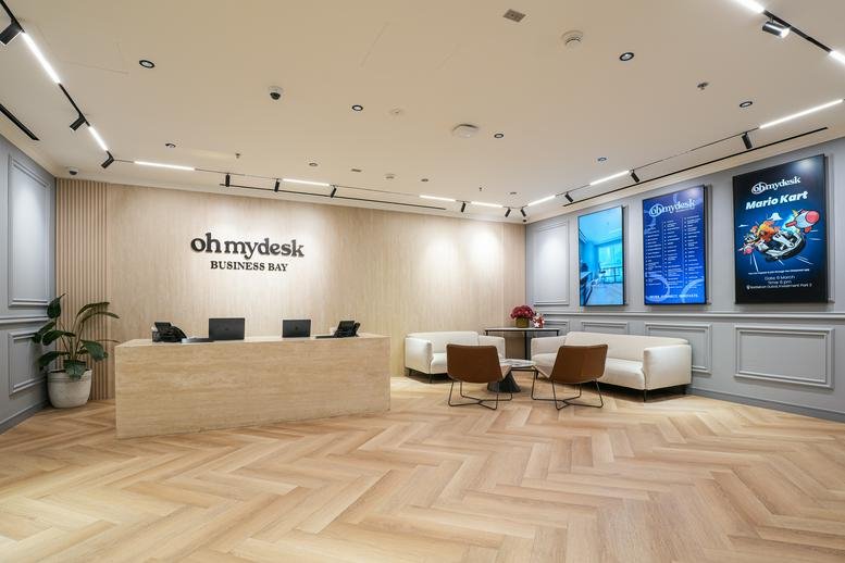 Wide view of a bright reception area with modern furniture and digital displays.