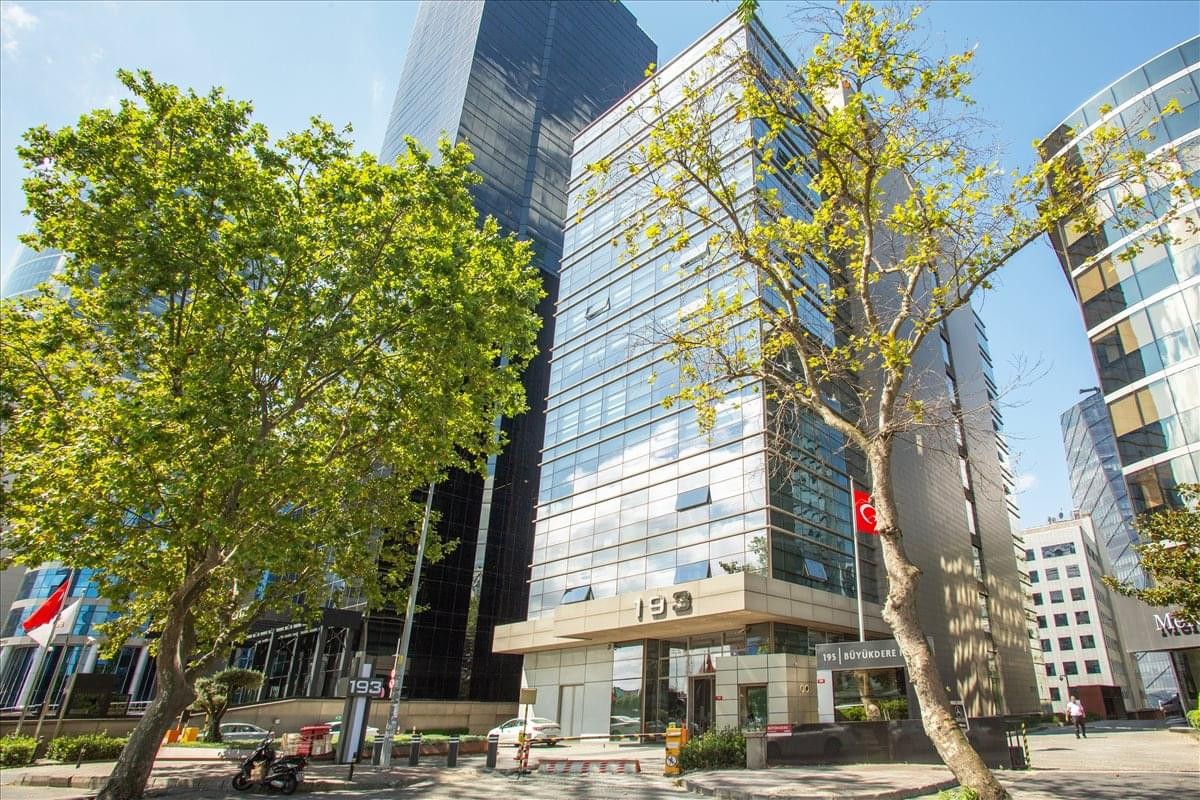 Exterior view of the modern glass-facade Levent No 193 Binasi surrounded by greenery.