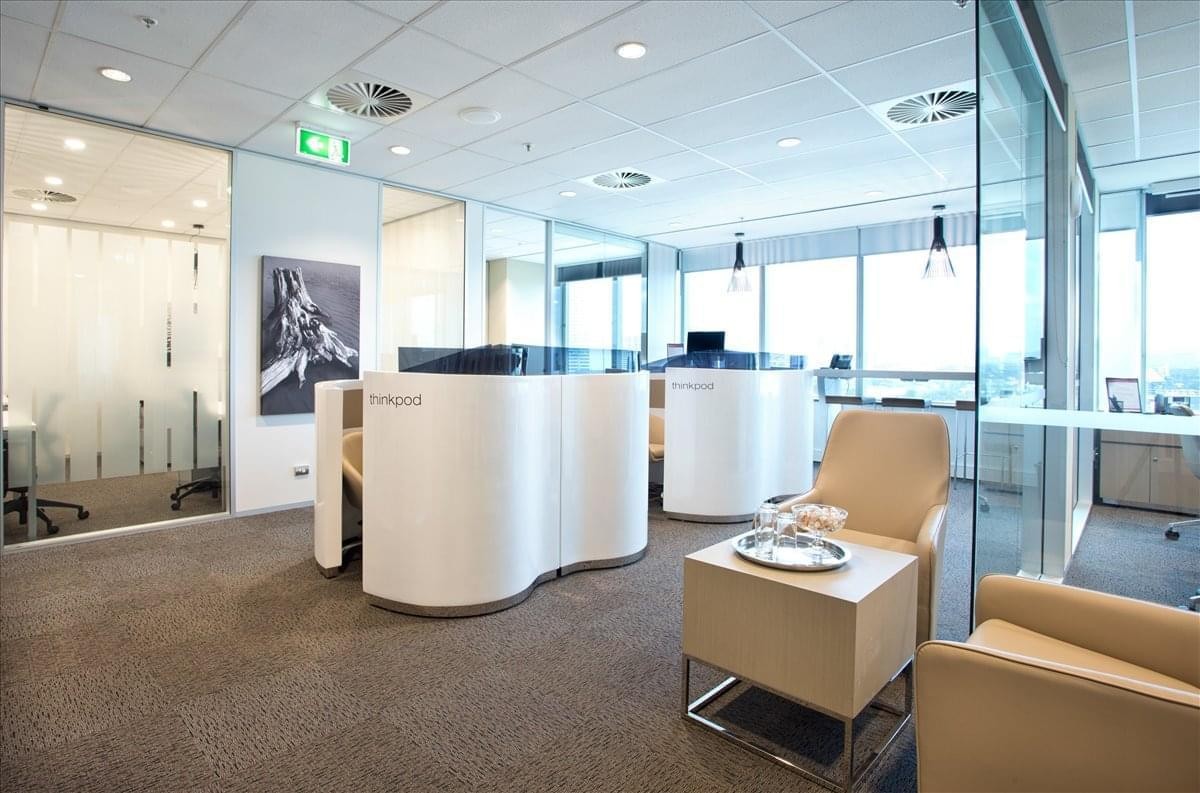 Bright reception area with unique curved white desks and tan leather armchairs.