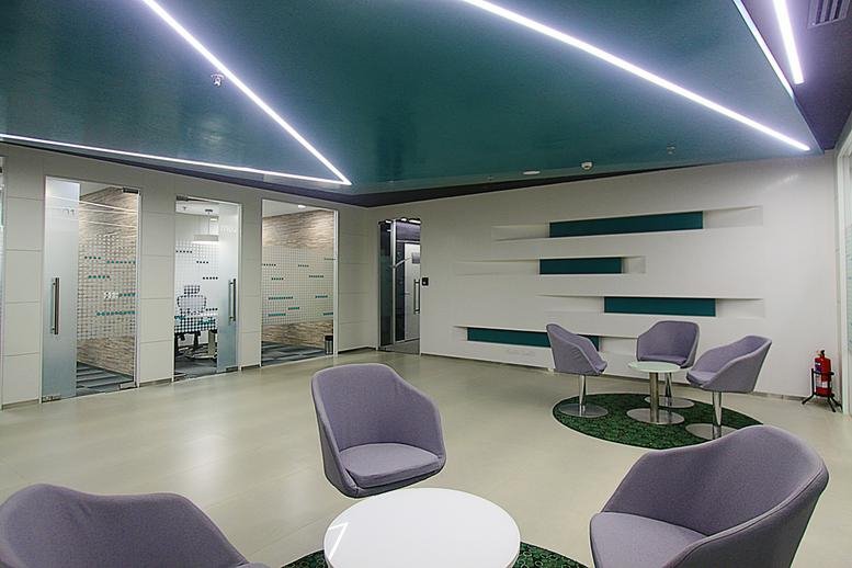Spacious reception lounge with purple armchairs and a dark teal geometric ceiling.