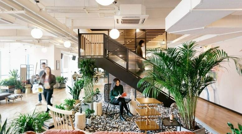 Bright lobby of the China Construction Steel Structure Building featuring a grand staircase and lush indoor plants.