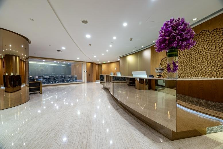 Modern reception lobby with a polished stone floor and a minimalist wooden welcome desk.