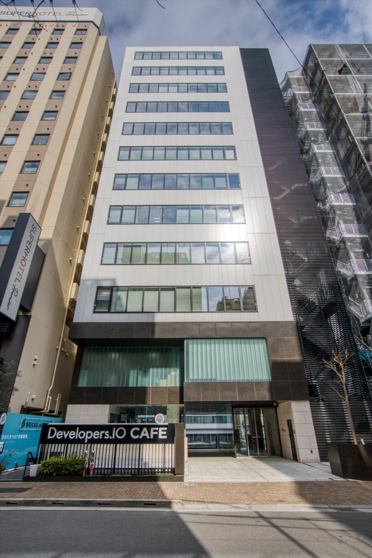Exterior view of the modern multi-story GYB Akihabara Building with a Developers.IO CAFE on the ground floor.
