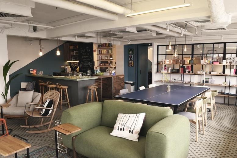 Communal lounge at Chung Kiu Commercial Building with a green sofa, ping pong table, and a coffee bar.