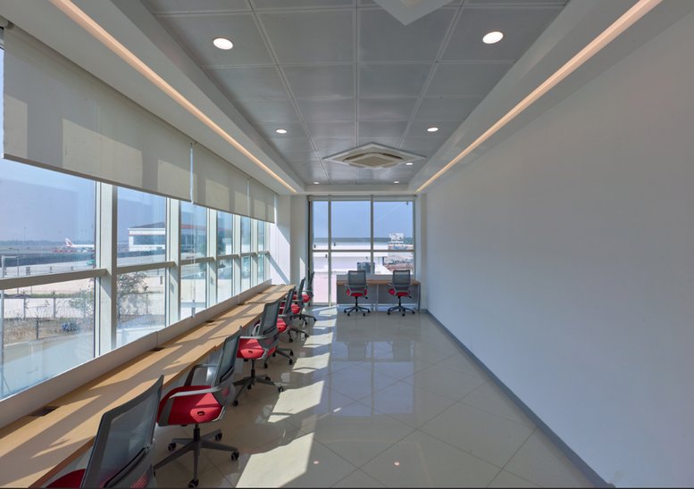 Long desk setup by large windows at CIASL Business Centre, CIAL Aeropark, Nedumbassery.