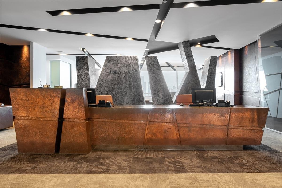 Grand reception desk at the Ciputra Office Tower featuring a textured metallic finish and geometric wall art.