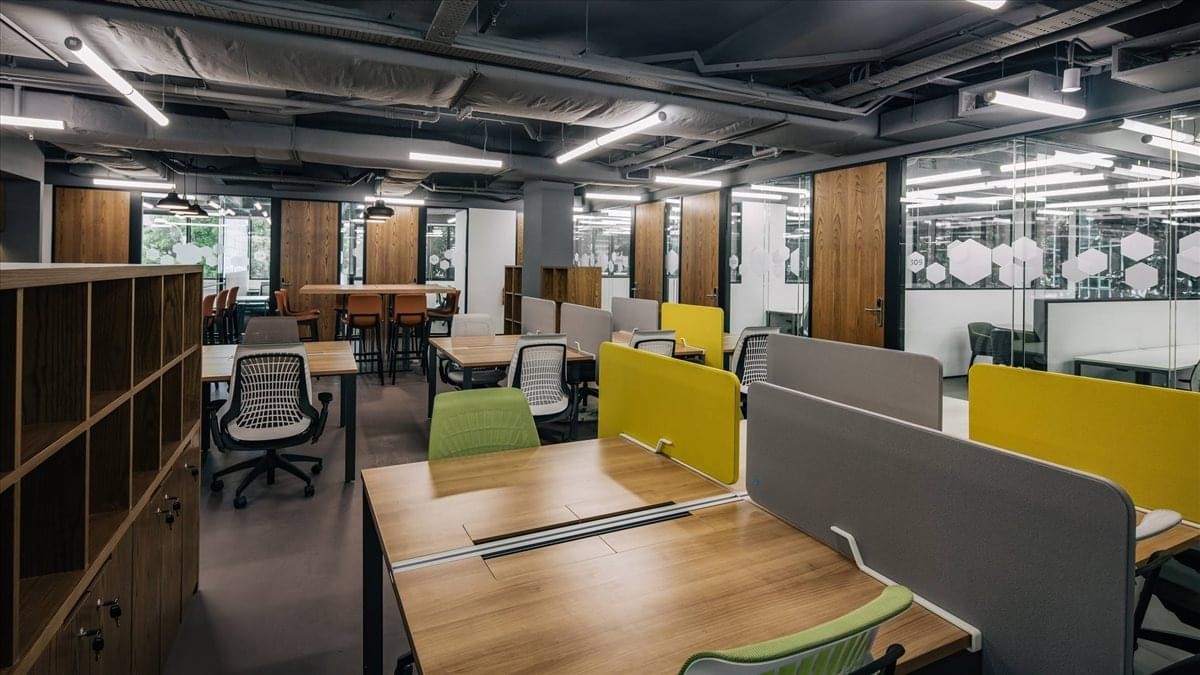 Modern open-plan workspace at City Hall, 410 North Bridge Road, Singapore featuring wooden desks and yellow partitions.