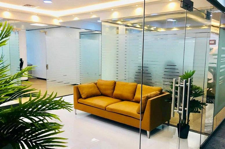 Reception area at City Tower 2, Sheikh Zayed Road, Dubai featuring a mustard yellow sofa and glass partitions.