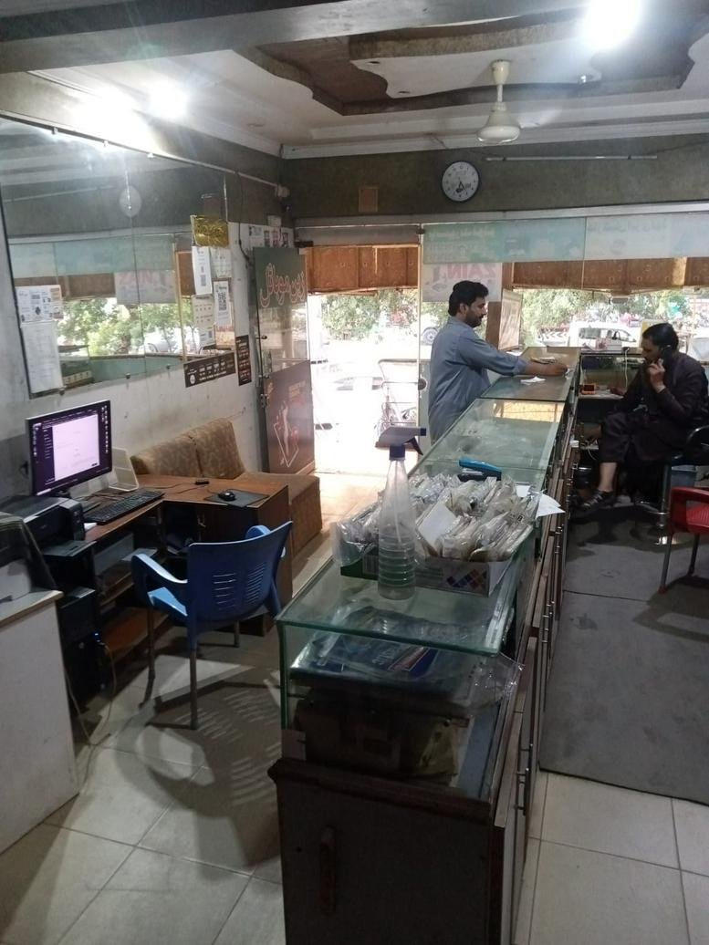 Reception and service area at College Road, Lahore, Pakistan with glass counters and computer workstations.