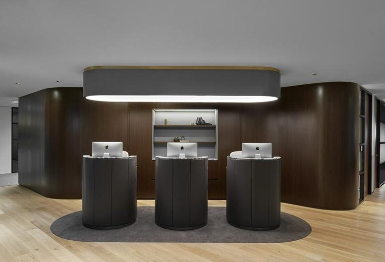Sleek reception area at Collins Square Tower 5 featuring three dark cylindrical desks and warm wood walls.