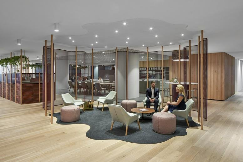Stylish lounge area with light blue chairs and pink ottomans on a uniquely shaped dark rug.