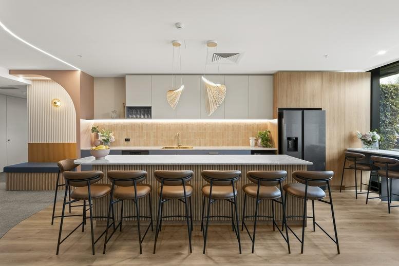 Modern kitchen and communal dining area at Corporate One, 84 Hotham Street with high-top seating and warm lighting.