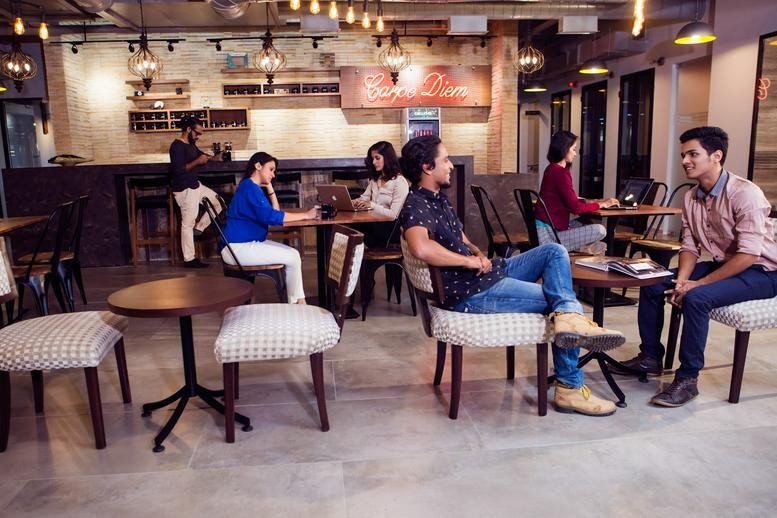 Spacious communal lounge at CoWrks Worli, Birla Centurion Century Mills Compound with warm lighting and café seating.