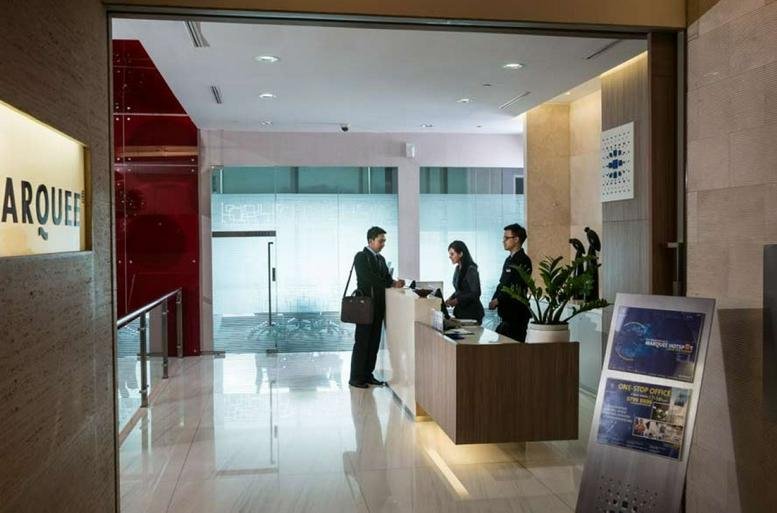 Modern reception area with staff standing behind a wood and white desk.