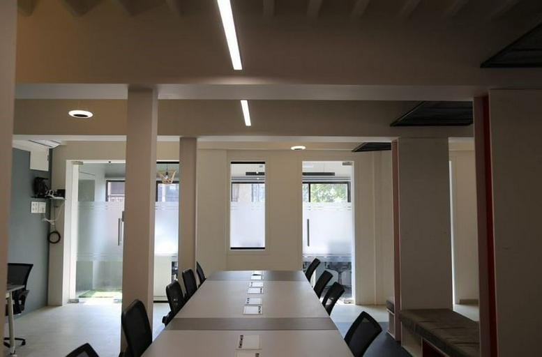 Spacious open-plan workspace at Daulatram Mansion featuring long white communal tables and bright linear lighting.